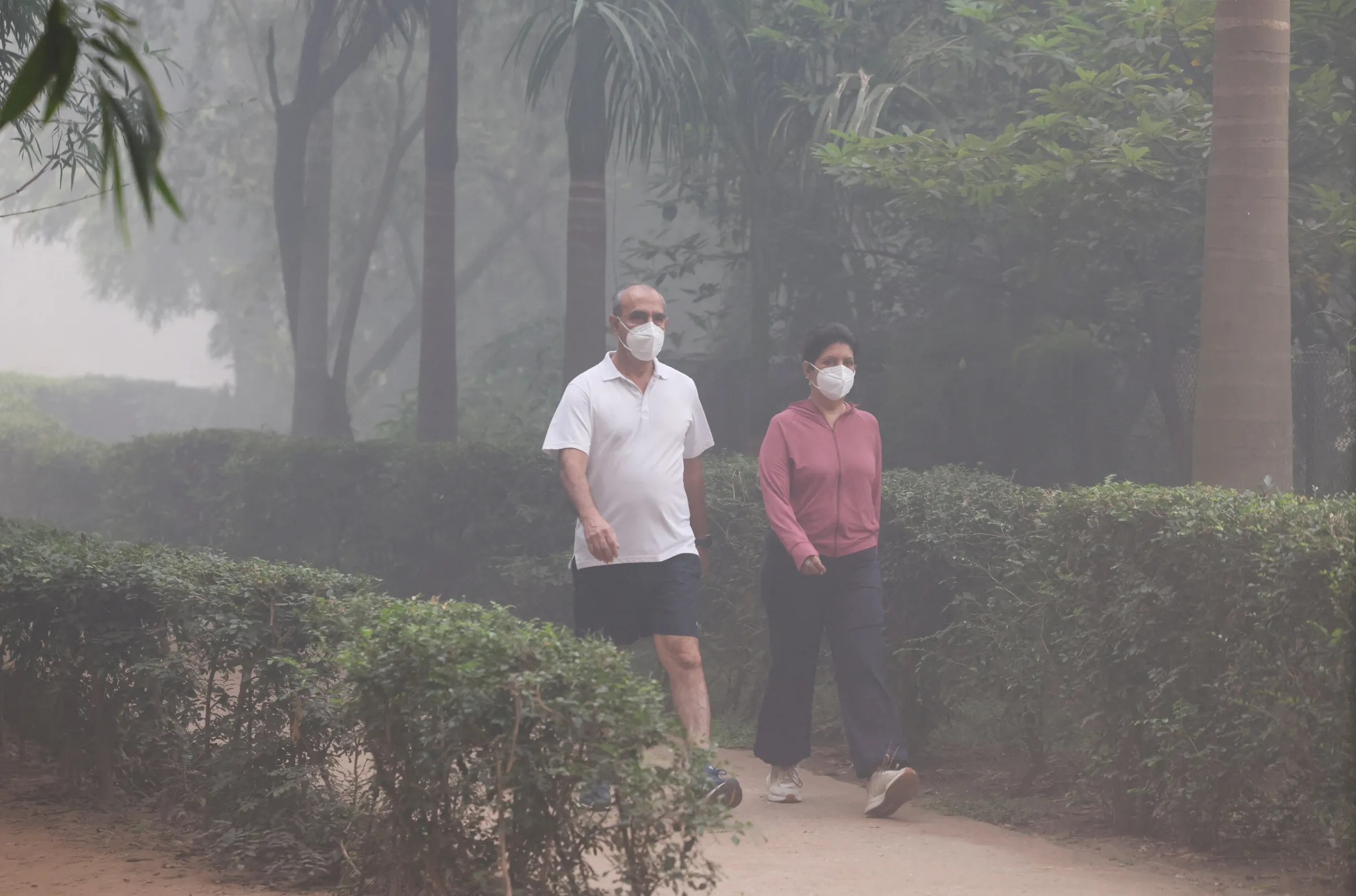 People walk wearing face masks at a park amidst smog on the day after Diwali, the Hindu festival of lights, in New Delhi, India, October 21, 2025. REUTERS/Bhawika Chhabra