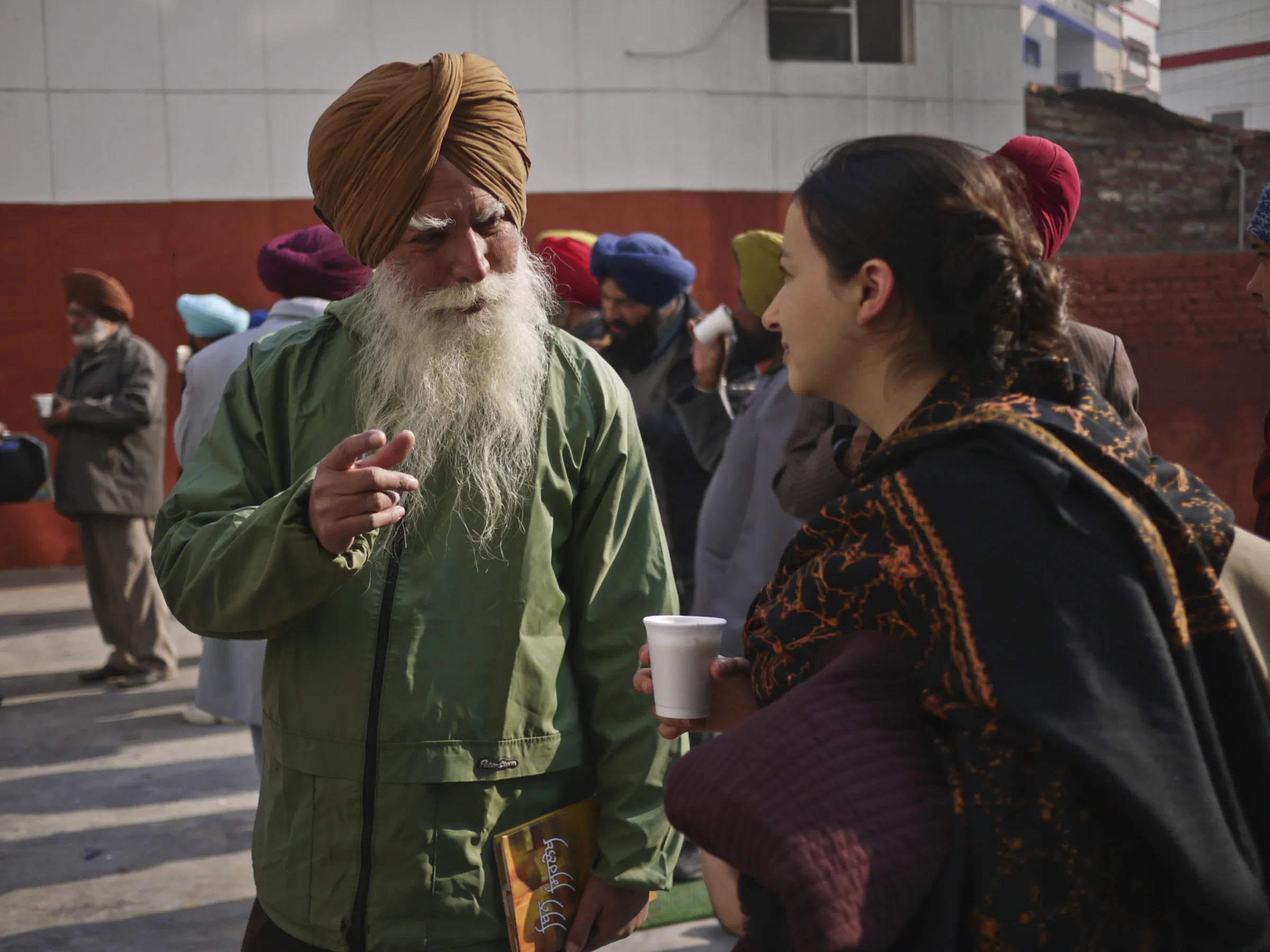 A man and a woman stand speaking in the steet