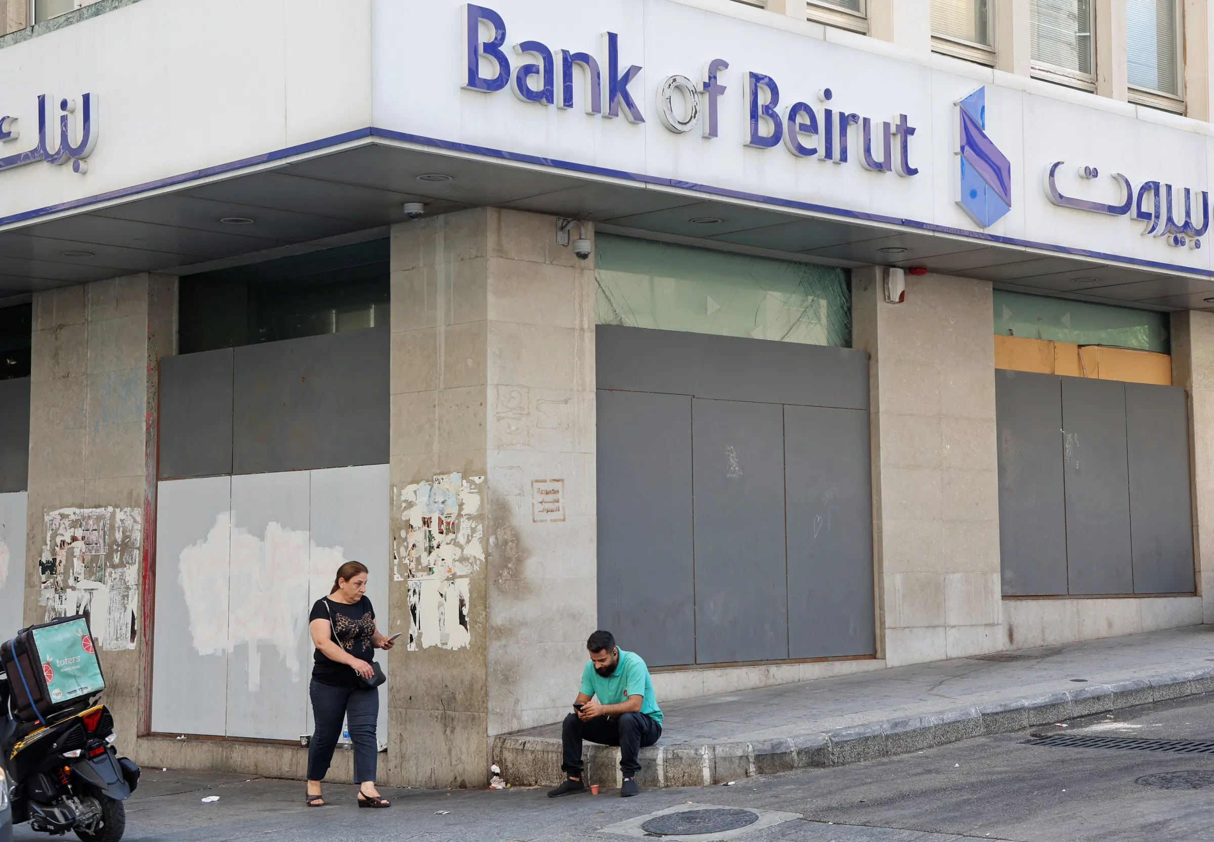 A man sits by a closed Bank of Beirut branch in Beirut, Lebanon September 20, 2022