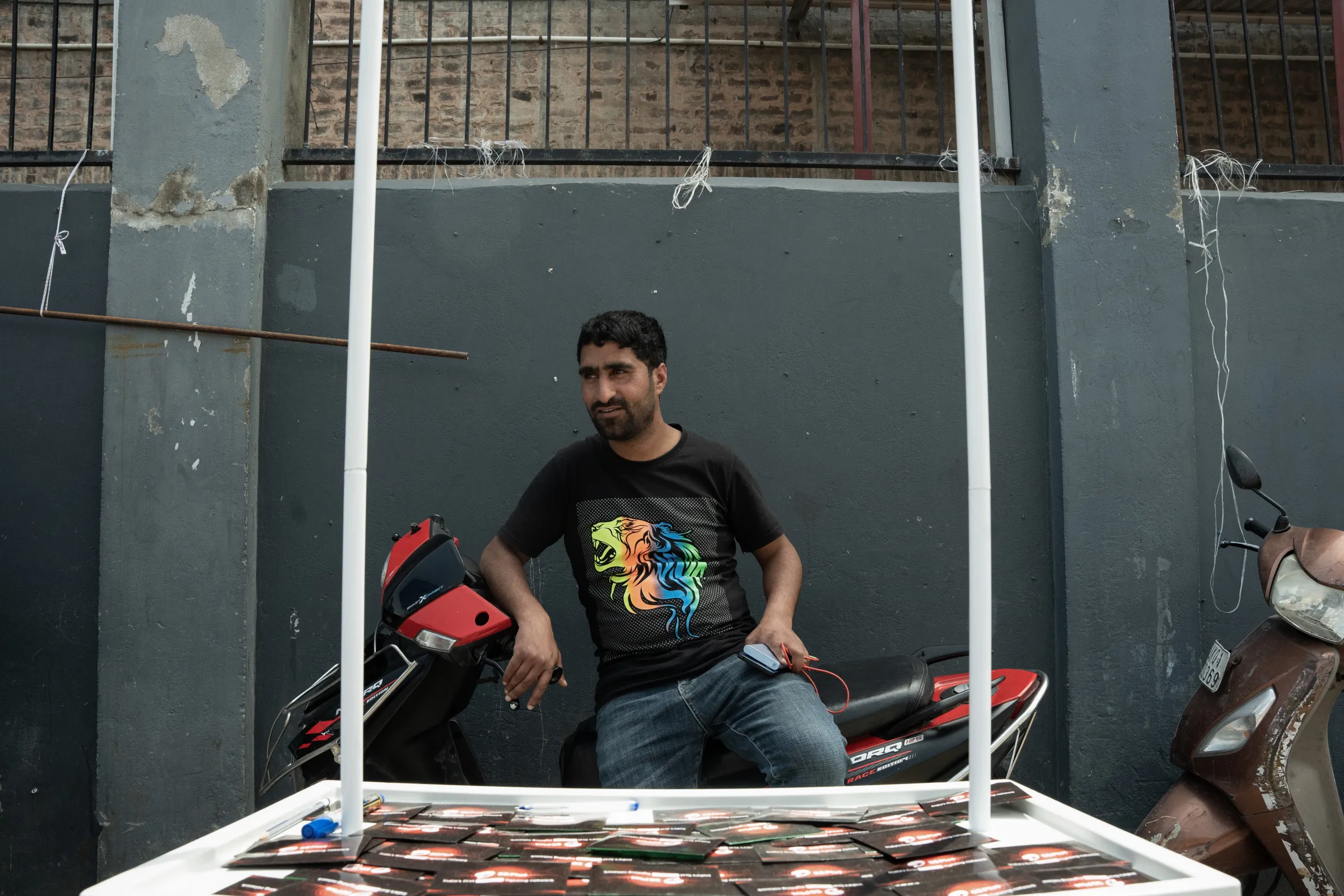 Abid Hussain Mir, 29, stands behind his SIM card stall in Srinagar. April 24, 2025. Mehran Firdous/Thomson Reuters Foundation