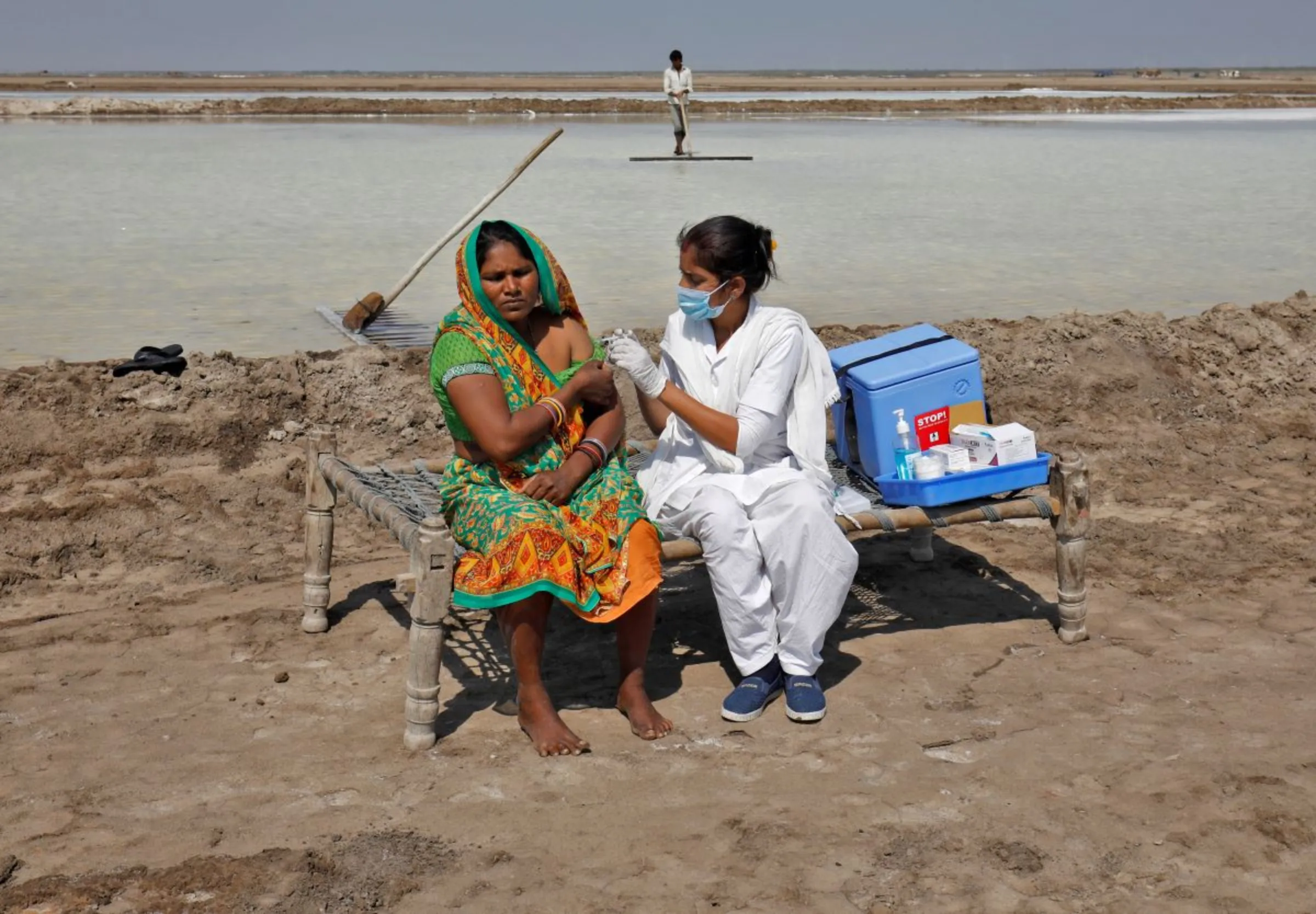 A healthcare worker gives a dose of vaccine against the coronavirus disease (COVID-19) to a worker at salt pan in Surendranagar district in the western state of Gujarat, India, February 18, 2022