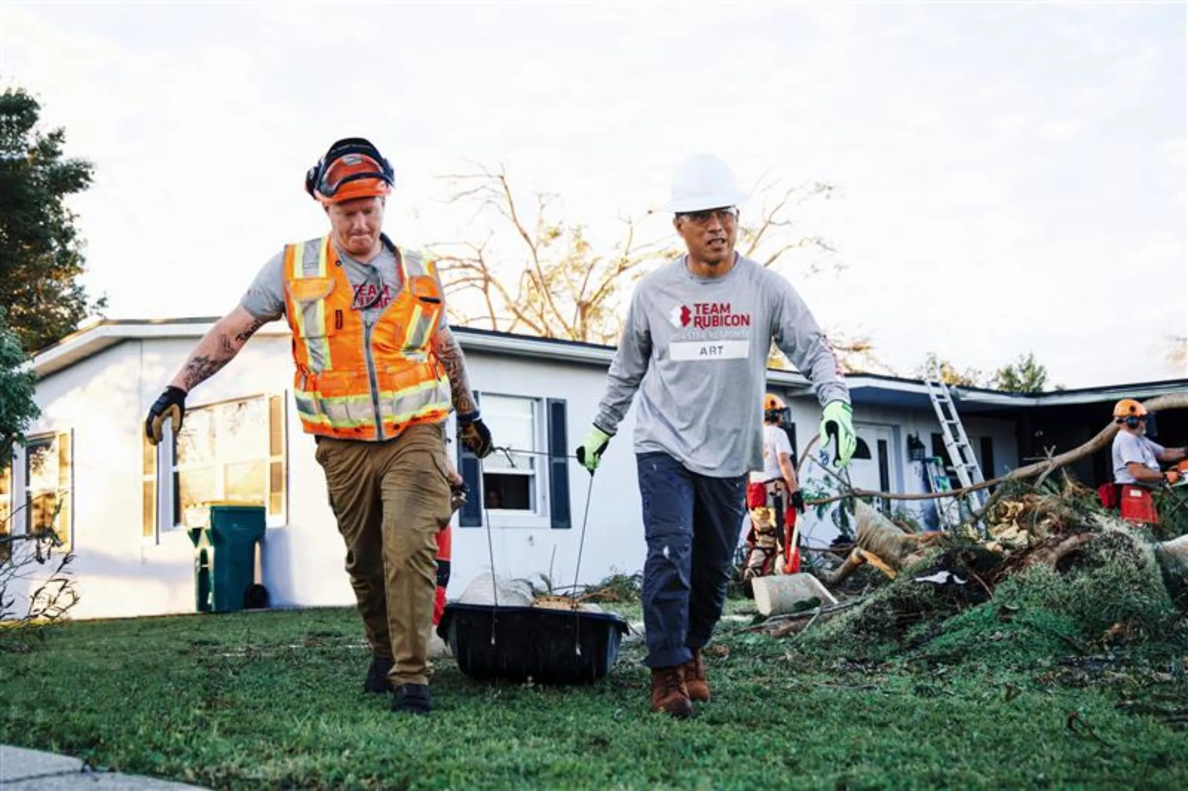 Art delaCruz, right, and Jacob Nilz pull debris amid post-storm cleanup operations in Port Charlotte, Florida, in October 2022 after Hurricane Ian made landfall. Andrew Dickason/Team Rubicon/Handout via Thomson Reuters Foundation