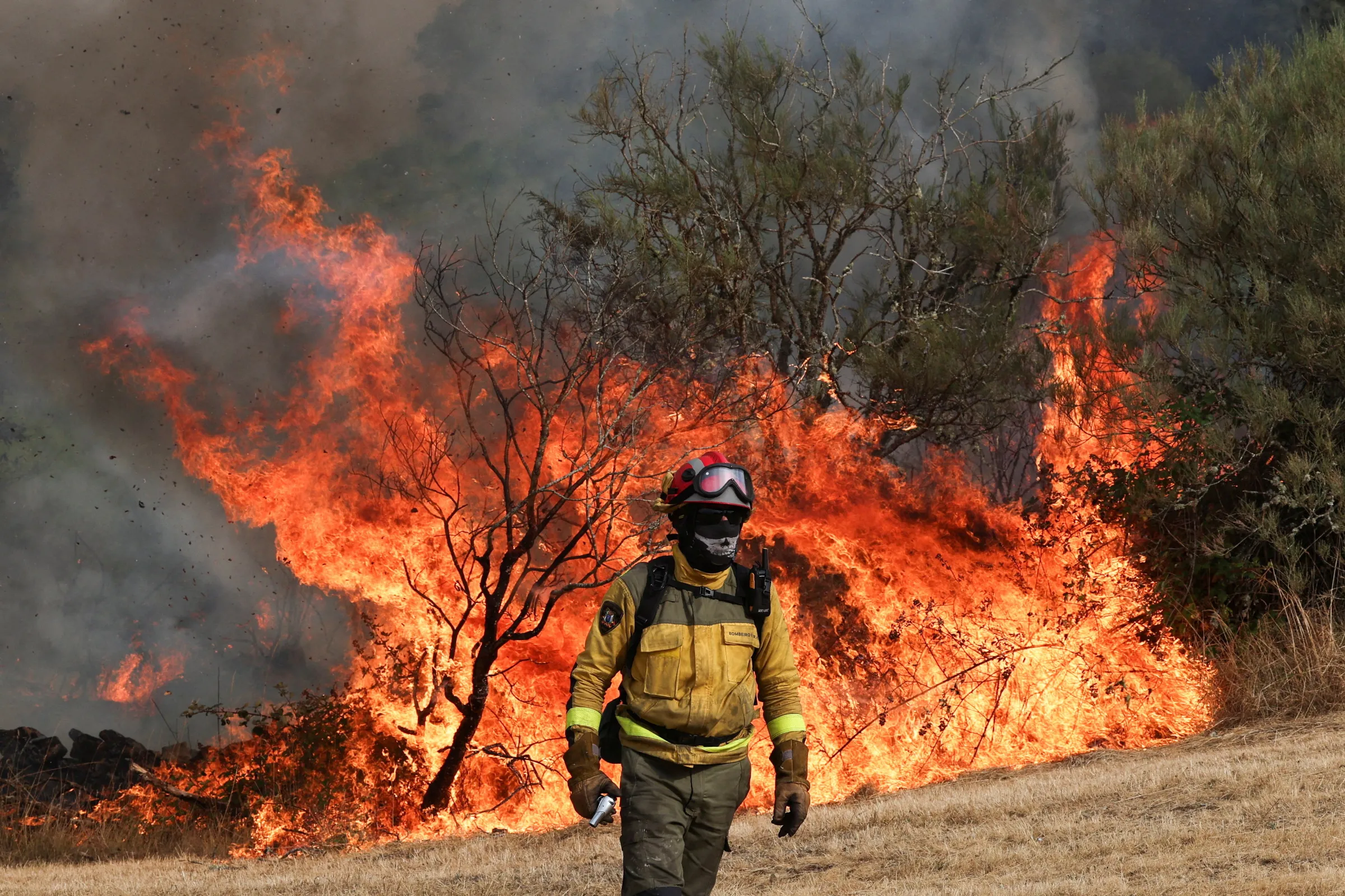 A firefighter changes position during operations to battle a wildfire in the village of Parafita, Galicia region, Spain, August 12, 2025. REUTERS/Violeta Santos Moura