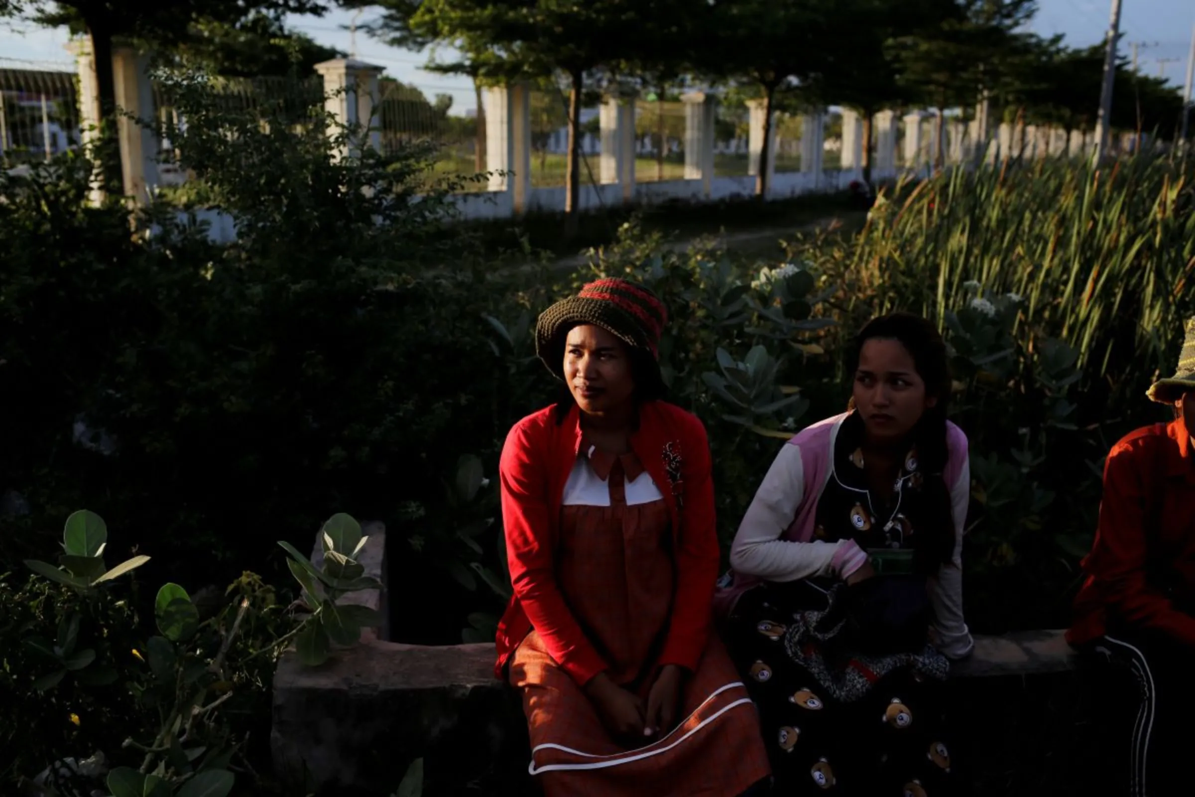 A nine months pregnant woman waits for a pickup truck to go home after work at a footwear factory, in Kampong Speu, Cambodia, July 4, 2018