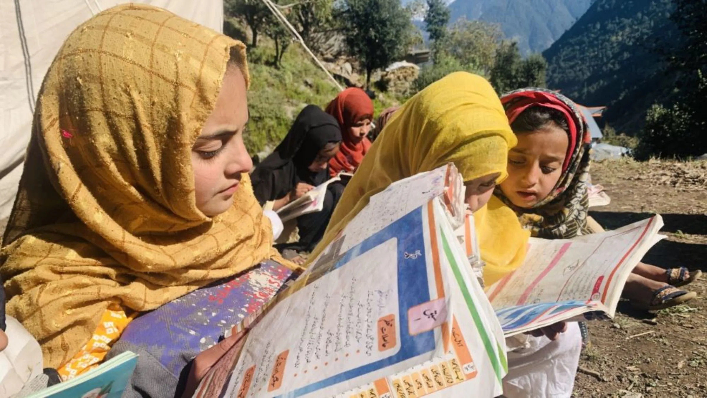 Sinain Bibi reads at a makeshift school in a village in Swat district in Pakistan’s northwest Khyber Pakhtunkhwa province, October 24, 2022