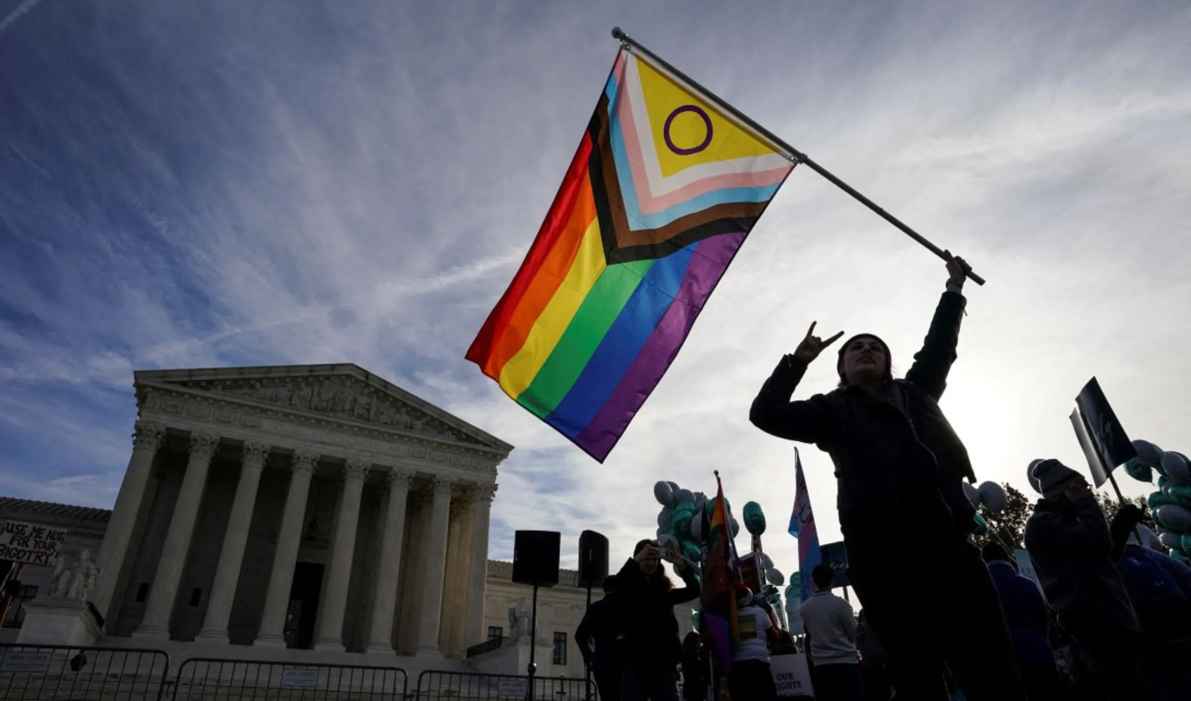 A protester waves an LGBT rights 'pride flag' as activists gather outside the U.S. Supreme Court in Washington, U.S., December 5, 2022. REUTERS/Kevin Lamarque