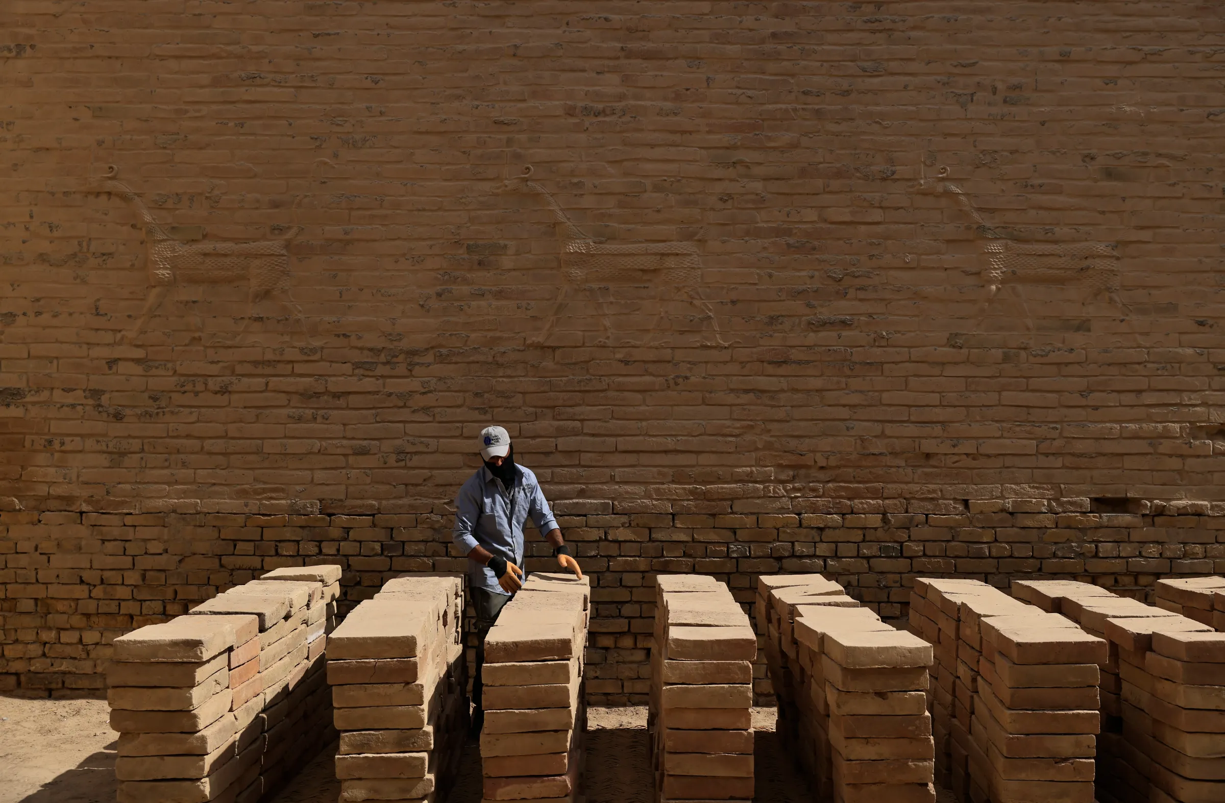 A worker from World Monument Fund sets out sun-crude bricks in the ancient city of Babylon, Iraq, October 13, 2022