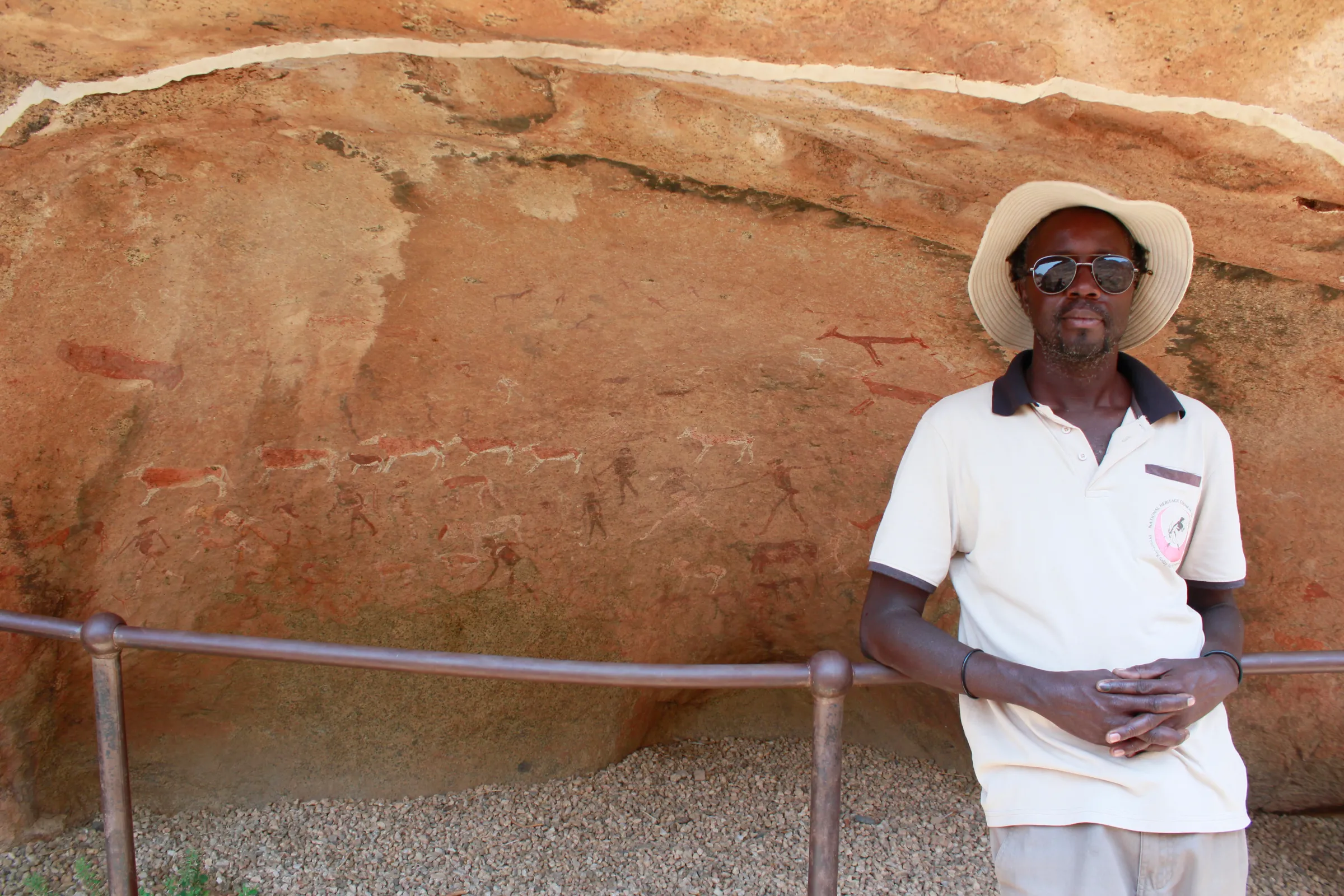 Rock art guide Tertius Oeamseb poses for a photo in front of a railing protecting the White Lady rock art in the Brandberg Mountain in west of Namibia, September 28, 2022