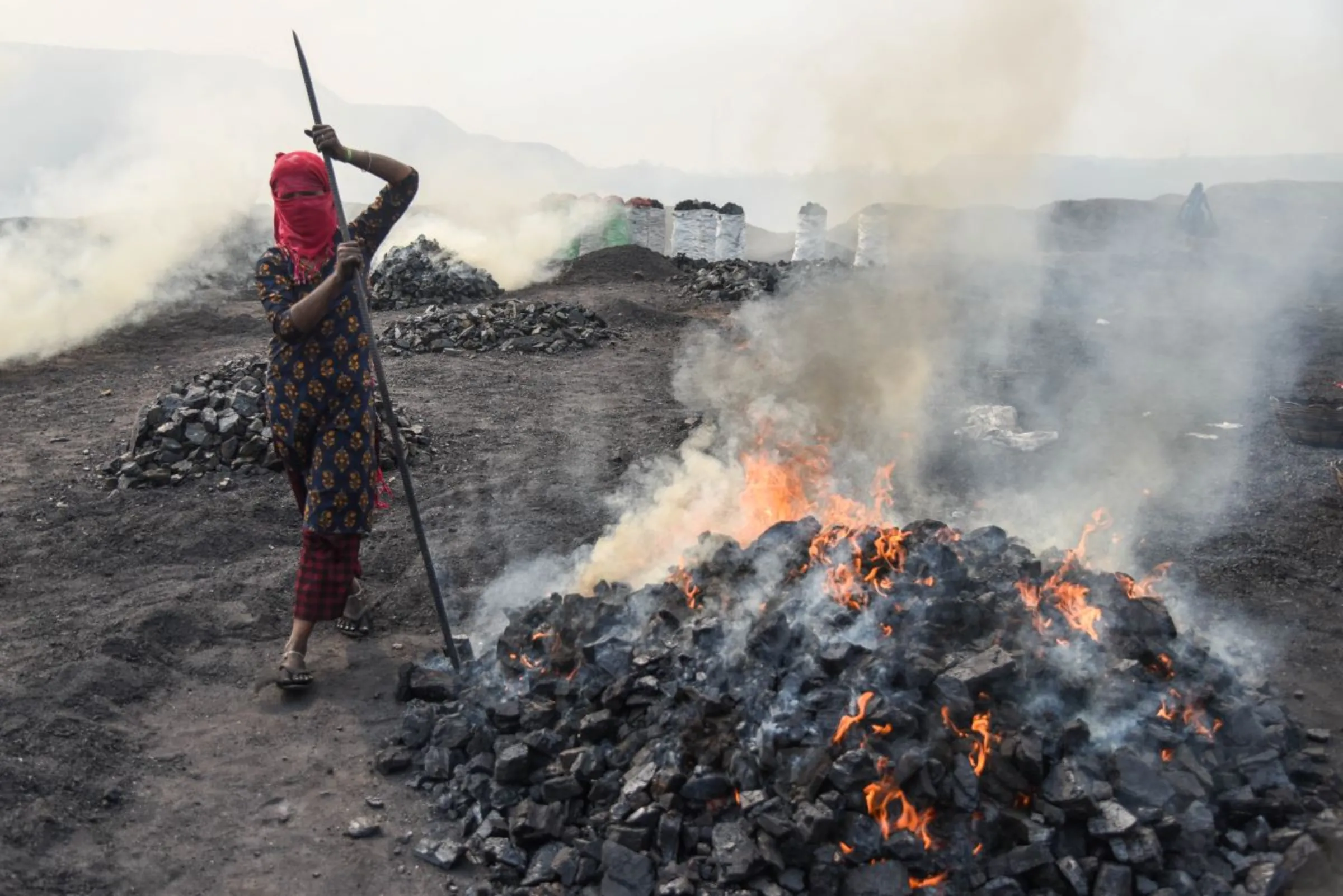 A coal scavenger Anita Devi burns coal before selling it for use at a depot in a mining area of Jharia coalfield, India, November 11, 2022. Thomson Reuters Foundation/Tanmoy Bhaduri