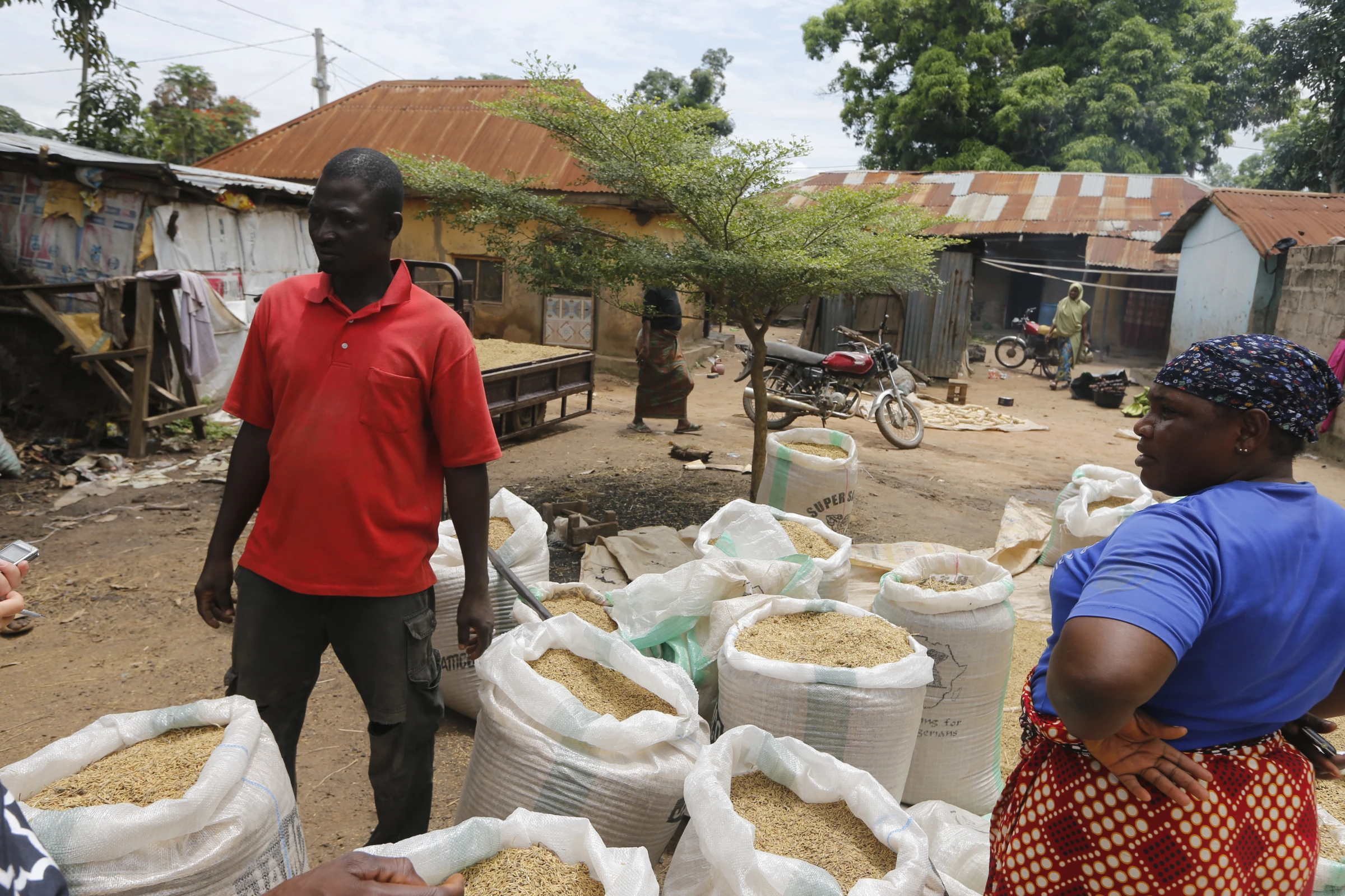Rice farmer Danjuma Okuwa stands next to bags of harvested paddy rice at his compound in Rukubi, Nasarawa, Nigeria, September 27, 2022. Thomson Reuters Foundation/Afolabi Sotunde