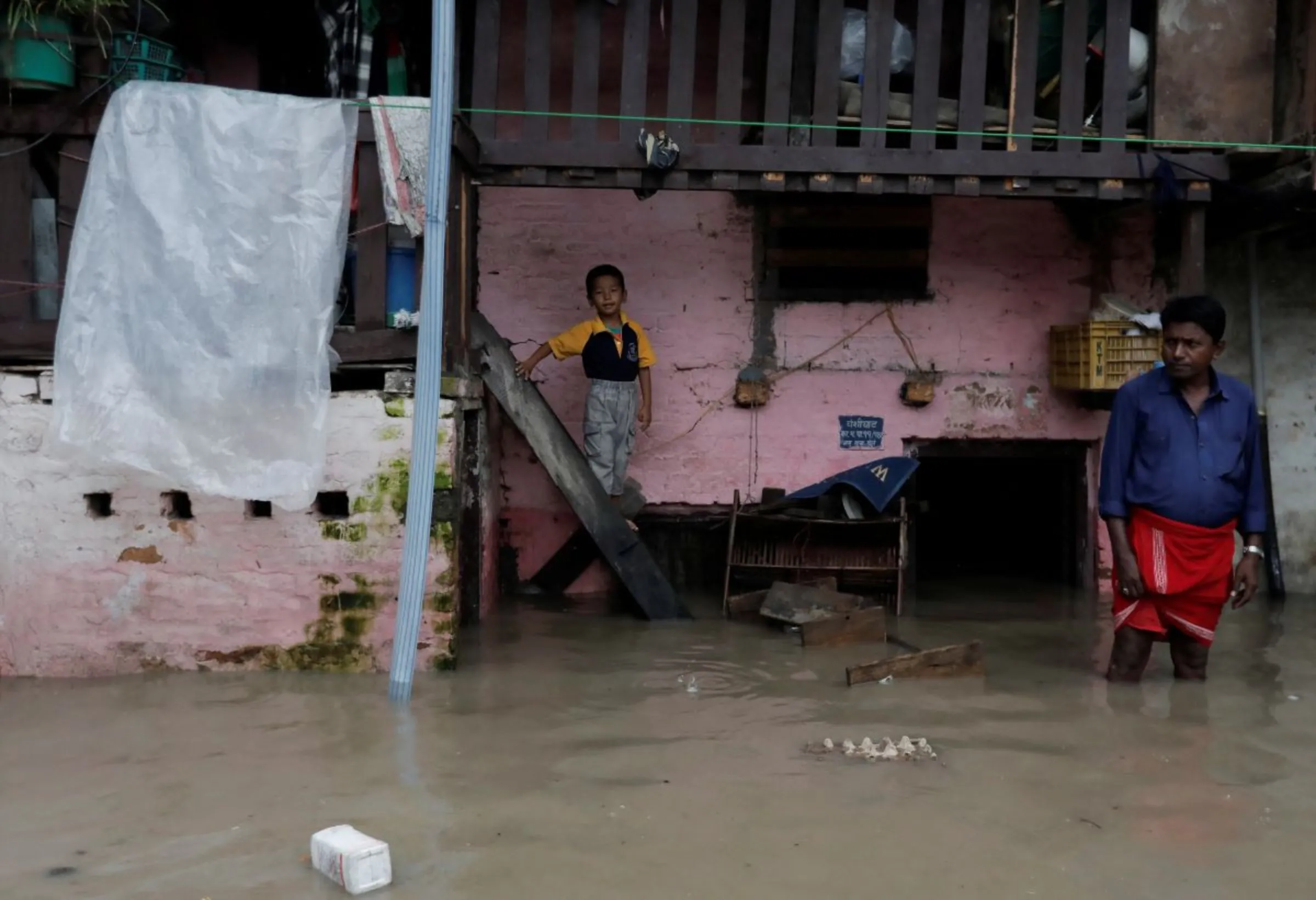 A boy stands on an entrance of his house in an area flooded by the overflowing Bagmati river following heavy rains, in Kathmandu, Nepal August 8, 2023